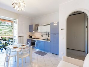 A modern kitchen with blue cabinets, a white countertop, and a dining area with a white table and chairs. - Nice apartment for 3 people with pool, WIFI, TV and balcony (Pietra Ligure)