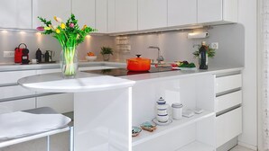 Una cocina moderna con armarios blancos, una isla central, horno empotrado y campana extractora de acero inoxidable.