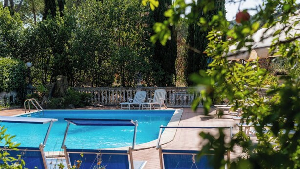 Une piscine avec des chaises longues et un mur en pierre.