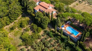 Une maison avec une piscine, entourée d’arbres et de collines.