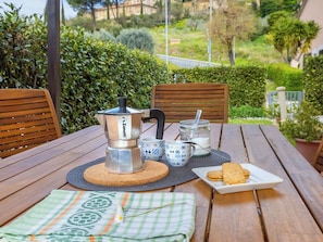 Ein Holztisch mit einer Kaffeekanne, Tassen, einem Einmachglas und einer Schüssel mit Keksen.