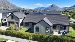Zona residencial con casas modernas, un césped cuidado y montañas al fondo.