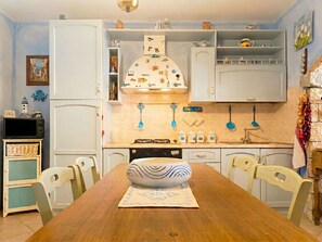 Ett kök med vita skåp, en köksö och ett matbord med stolar.