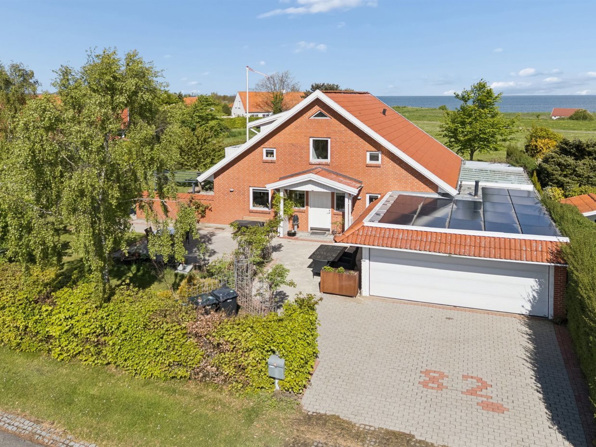 Une maison à deux étages avec un garage, un toit en pente et une allée pavée.