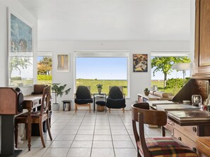 Ein geräumiger Wohnbereich mit Blick auf die Landschaft, ein Esstisch, Stühle und eine Couch.