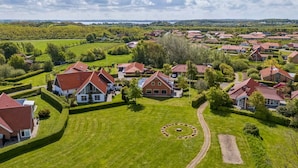 A residential area with houses, green lawns, and a circular stone arrangement.
