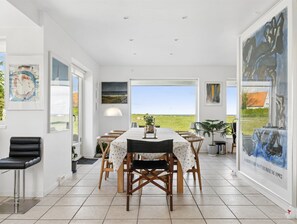 Ein Essbereich mit Tisch und Stühlen, ein schwarzer Stuhl, eine Lampe und Kunstwerken an den Wänden.