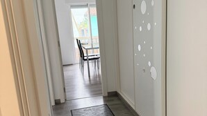 Ein Flur mit Holzboden, einer schwarz-weißen Streifenmatte und einer Tür mit runden Ausschnitten.