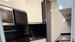 Eine Küche mit einem schwarzen Kühlschrank, weißen Schränken, einer Edelstahl-Spüle und einer schwarzen Arbeitsplatte.