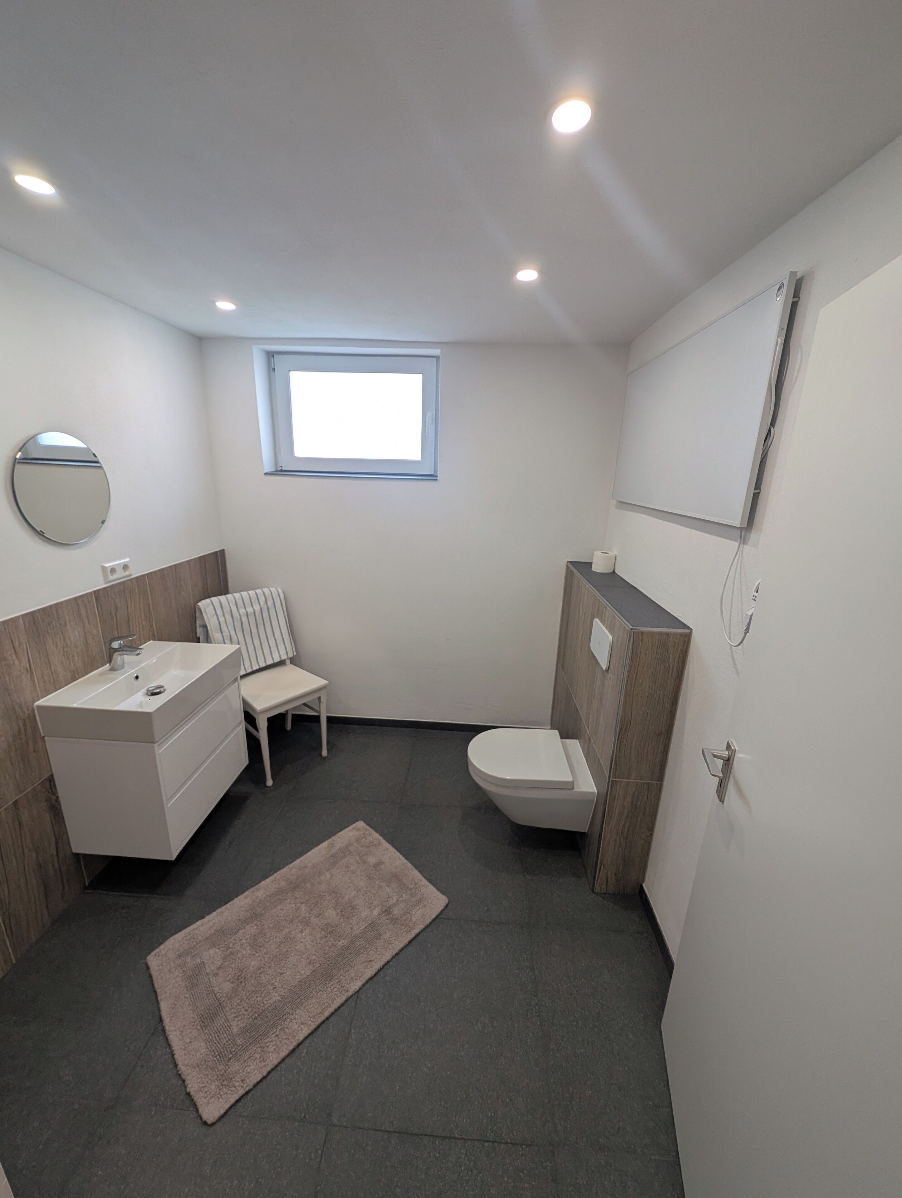 Un baño moderno con tocador, inodoro y un ventanal.