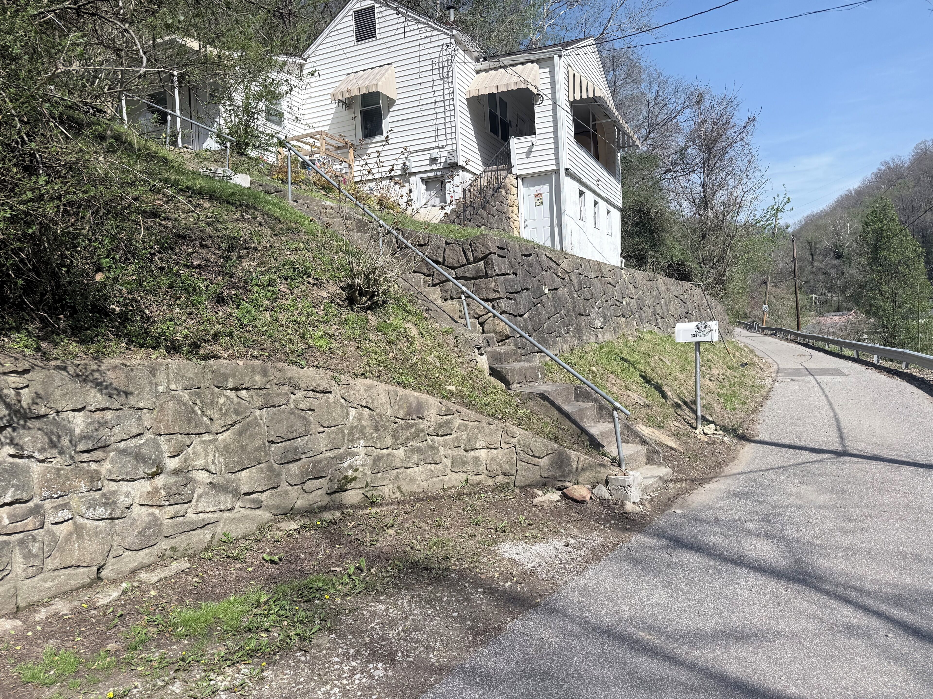 Une maison à deux étages avec un mur de soutènement en pierre et une allée pavée.