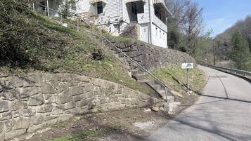 Une maison à deux étages avec un mur de soutènement en pierre et une allée pavée.