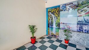 Un pasillo con piso a cuadros, plantas en macetas y un mural que representa una cascada y un jardín.
