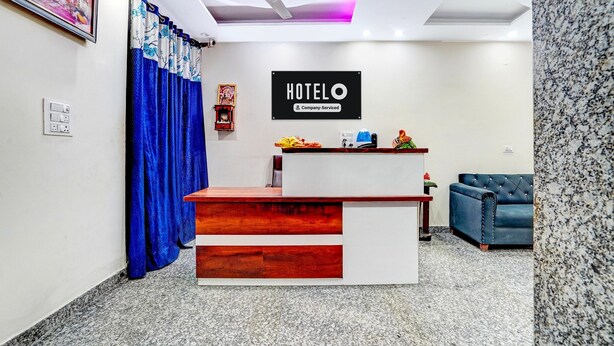 Un mostrador de recepción de hotel con un cartel, un ventilador de techo, una cortina azul, un sofá azul y un piso de granito.
