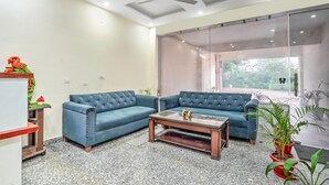 Una sala moderna con un sofá seccional, una mesa de centro de vidrio y un ventilador de techo.