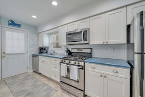 A kitchen with white cabinets, a stainless steel stove, a microwave, and a refrigerator.