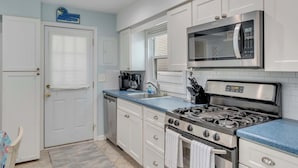 A kitchen with white cabinets, a stainless steel microwave, a gas stove, and a sink. - Oceanview Beach Retreat (Wildwood Crest)