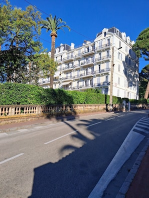 Ein mehrstöckiges Gebäude mit Balkonen, wolkenlosem Himmel und einer Straße mit Zebrastreifen.