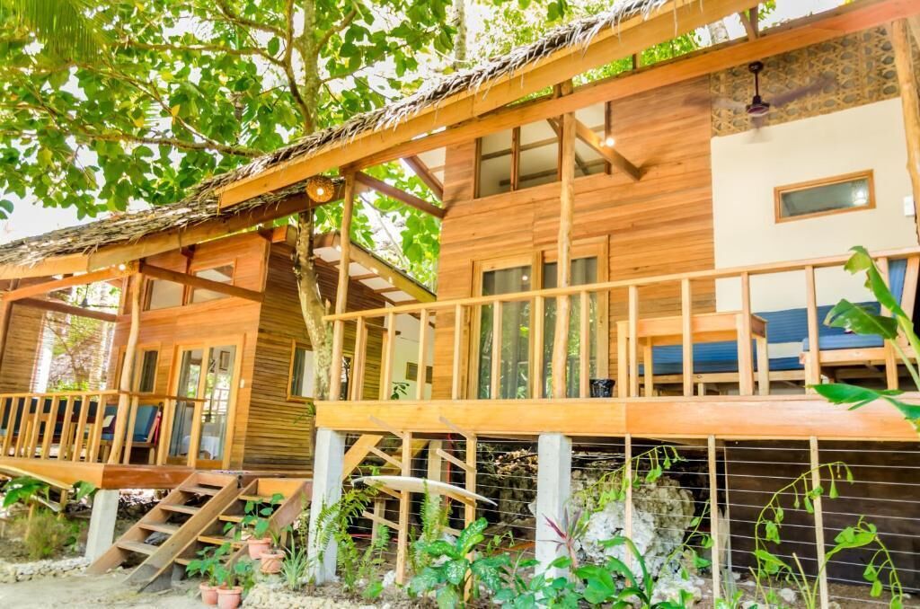 A wooden cabin with a balcony, a staircase, and a window.