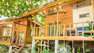 A wooden cabin with a balcony, a staircase, and a window.