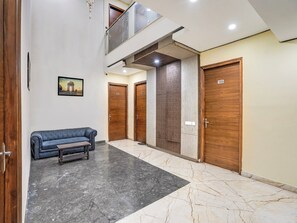 Eine Hotelhalle mit Marmorboden, einer blauen Couch, Holztüren und einem gerahmten Bild an der Wand.