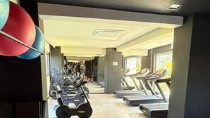 Een fitnessruimte met trainingsapparatuur, banken en loopbanden.