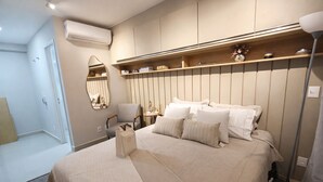 Een keurig opgeruimde hotelkamer met een bed, nachtkastje, stoel en spiegel.
