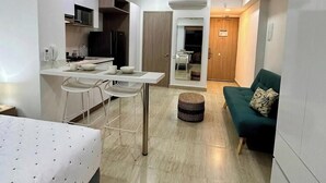 Un espacio habitable compacto con kitchenette, comedor, sofá y cama.
