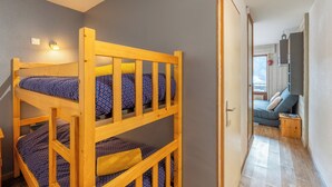 Un lit superposé avec une tête de lit, une petite table de chevet et une lampe fixée au mur.