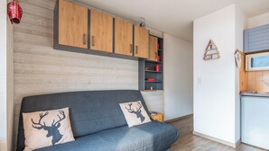 Un espace de vie moderne avec un canapé gris, des meubles en bois et un petit coin cuisine.