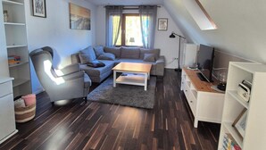 Een moderne woonkamer met een bank, een salontafel, een boekenkast en een bureau.