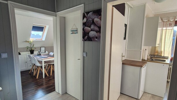 Een moderne keuken met een inbouwoven, een eethoek met tafel en stoelen, en een klein raam met uitzicht.