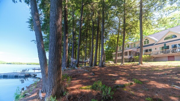 A lakeside property with a wooden deck, a swimming pool, and a large house with a porch. - Lakefront Peninsula Retreat w/Private Dock, on Cobbosseecontee Lake, 4 BR (West Gardiner)