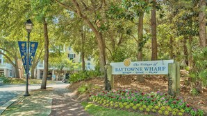Een bord voor The Village of Baytowne Wharf, met een pad dat naar een gebouw leidt.