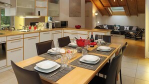 Un coin repas avec une longue table dressée pour quatre personnes, agrémentée d’assiettes, de verres et de couverts.