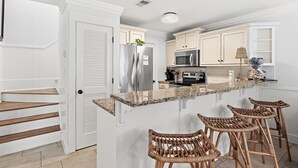 A kitchen with a central island, stainless steel appliances, and wicker bar stools. - ☀️Walk to Beach | 30A | Casa Azule- Blue Mountain Beach☀️ (Santa Rosa Beach)