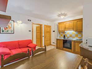 Ein kompakter Wohnbereich mit Küchenzeile, einem Holzesstisch, einem roten Sofa und Holztüren.