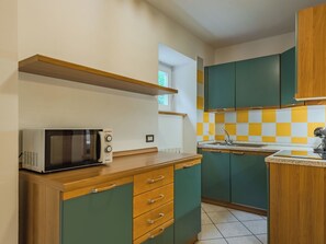 Une cuisine équipée d’un four à micro-ondes, de meubles en bois, d’un crédence à carreaux et d’une fenêtre.