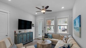 A living room with a sofa, chairs, a coffee table, a television, and a ceiling fan. - ☀️Walk to Beach | 4 Bikes | Game Room | Emerald Escape 30A🏖 (Santa Rosa Beach)