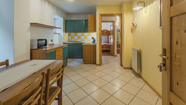 Eine kompakte Küche mit Essbereich, ein kleines Badezimmer und ein Schlafzimmer mit Etagenbett.