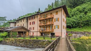 Ein mehrstöckiges Hotel mit Balkonen, einer Holzterrasse und einem Fluss im Vordergrund.