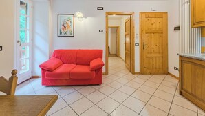 Ein Zimmer mit einem roten Sofa, Holztüren und einem Fliesenboden.