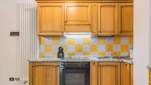 Eine Küche mit Holzausstattung, einem Backofen, einem Geschirrspüler und einer karierten Spritzschutzwand.