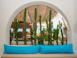 Ein Sitzbereich mit Blick auf eine Terrasse und Kakteen, die einen Pool und einen Außenbereich zum Essen überblickt.
