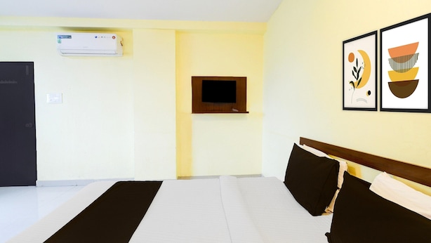 Une chambre d’hôtel avec un lit, un téléviseur fixé au mur et un appareil de climatisation.