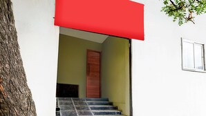 Un escalier menant à une porte, un arbre et une fenêtre sur un bâtiment.
