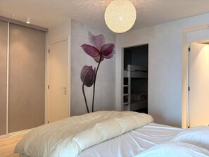Ein Schlafzimmer mit einem Etagenbett, einer Wandleuchte und einer Tür zu einem anderen Raum.