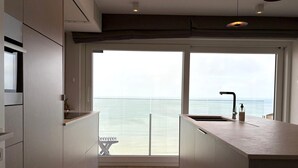 A modern kitchen with a large window overlooking the sea, a built-in bench, and a minimalist design. - Apartment With sea View in Middelkerke for 6 (Middelkerke)