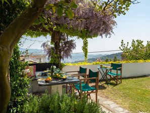 An outdoor dining area with a table set for two, surrounded by greenery and a view of the landscape. - Bellissimi e Paola by Interhome (Dolcedo)