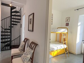Ein Zimmer mit einem Etagenbett, einer Treppe und zwei Stühlen mit gemusterten Kissen.